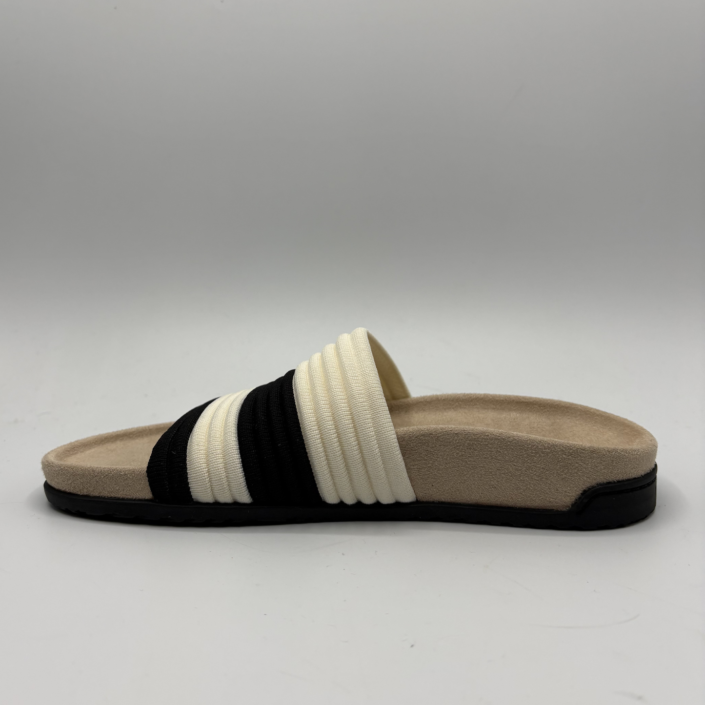 Beige sandal with black and white straps on a gray background