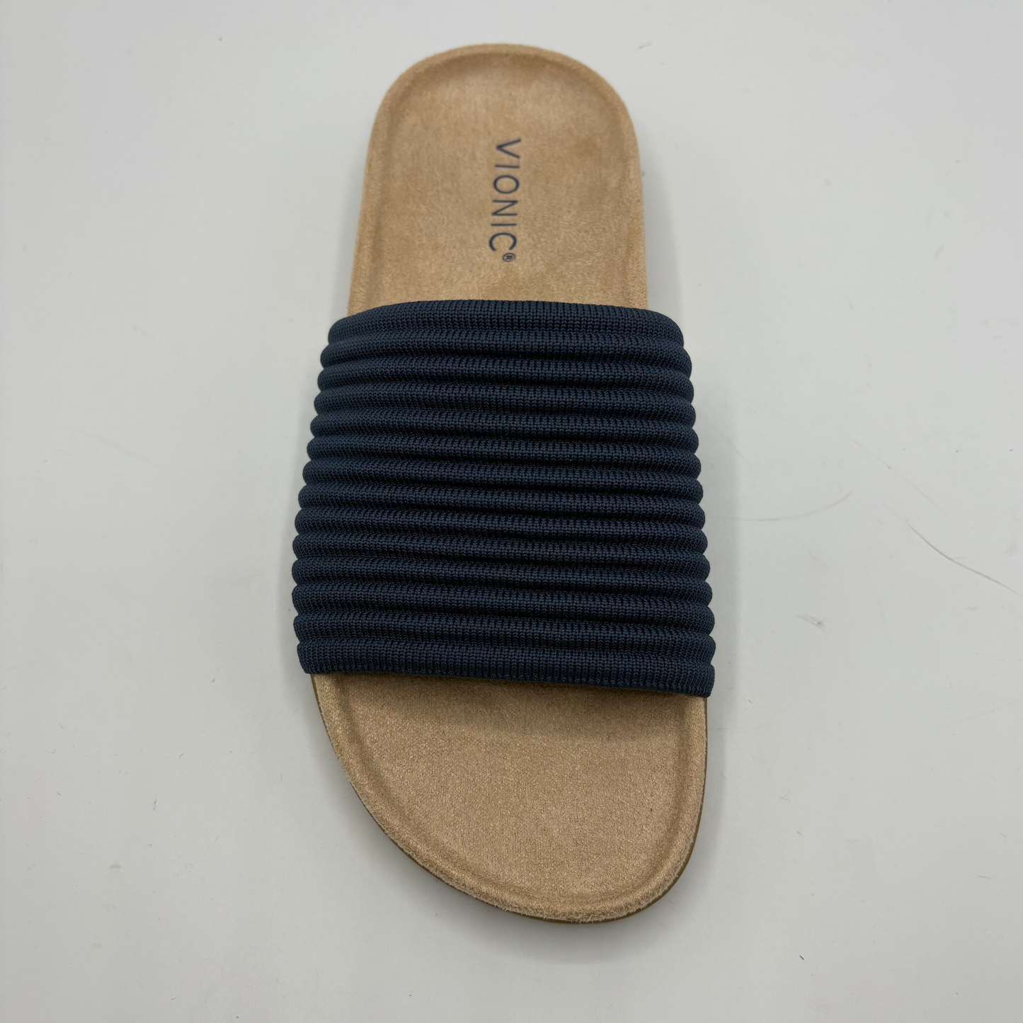 Beige sandal with navy blue elastic band on a light gray background