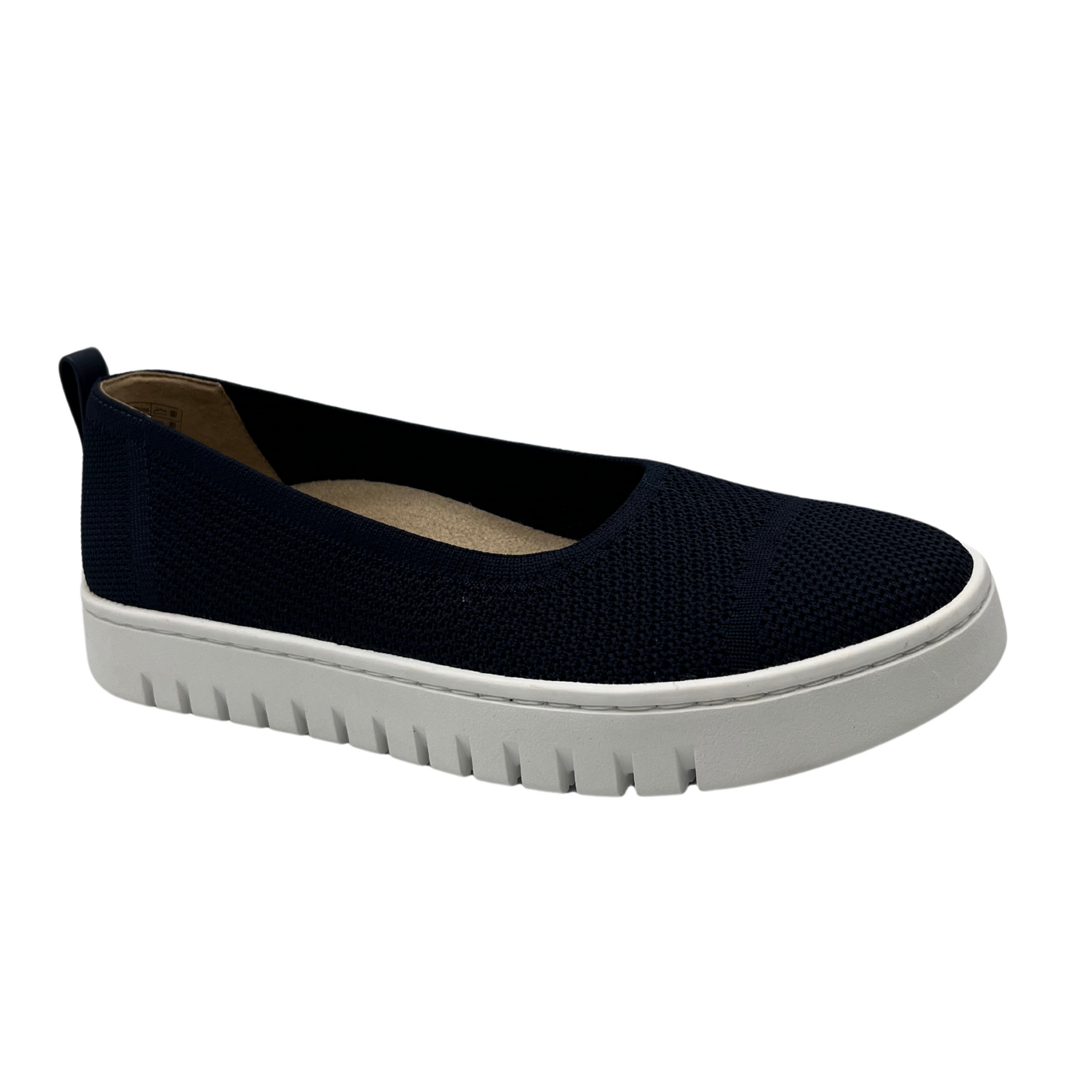 45 degree angled view of navy knit flat shoe with removable insole, rounded toe and pull on heel tab.