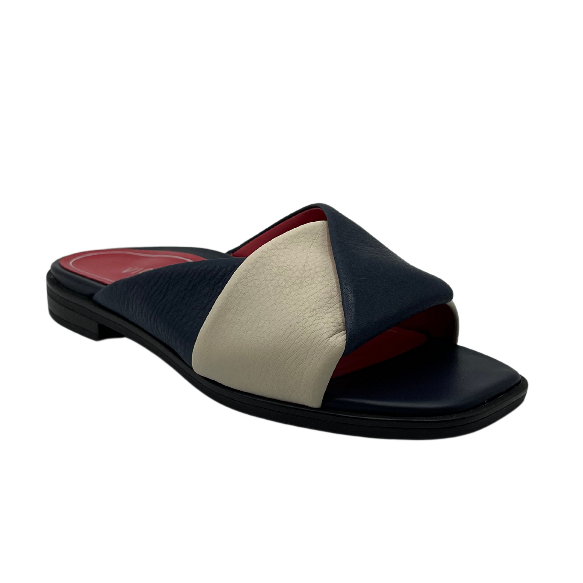 45 degree angled view of navy and cream leather slip on with red inner lining and square toe