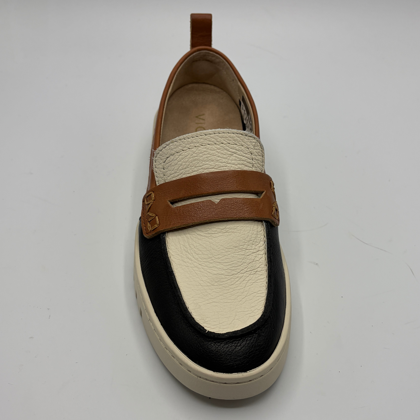 Loafer shoe with brown strap and black and beige sole on a white background