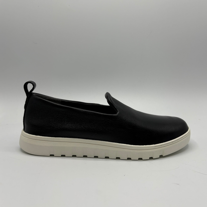 Black slip-on shoe with a white sole on a gray background