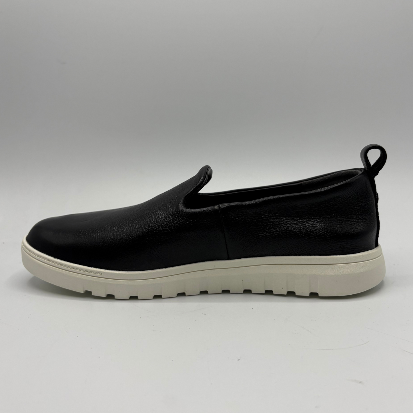 Black slip-on shoe with a white sole on a gray background