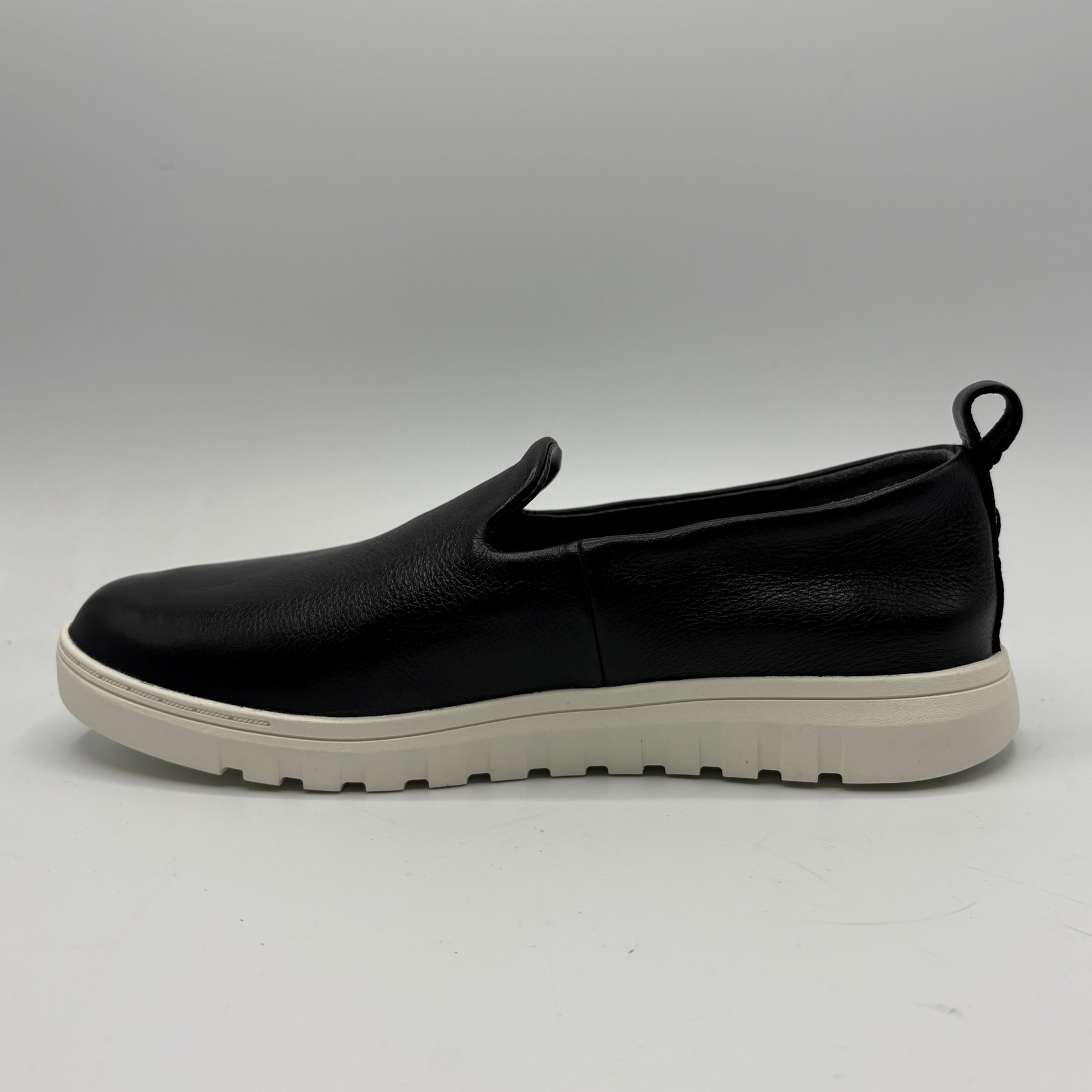 Black slip-on shoe with a white sole on a gray background