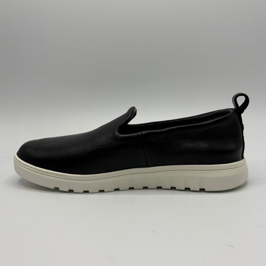 Black slip-on shoe with a white sole on a gray background