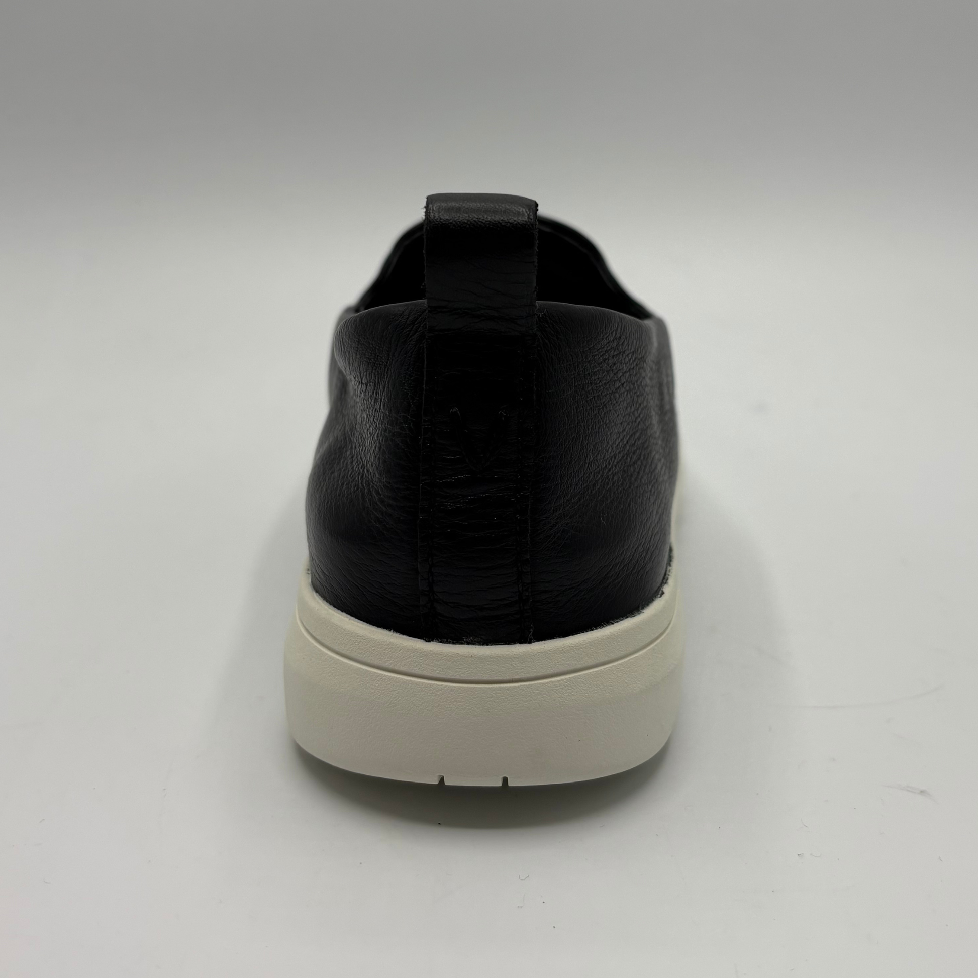 Black slip-on sneaker with a white sole on a light gray background