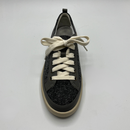 Grey sneaker with white laces on a light gray background