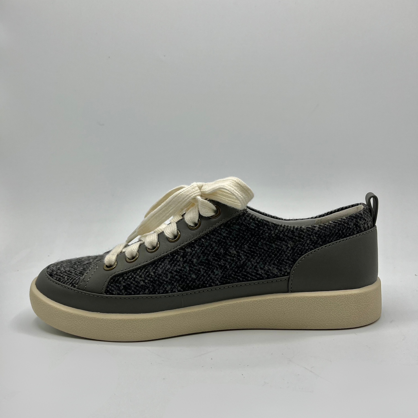 Grey sneaker with white laces on a gray background