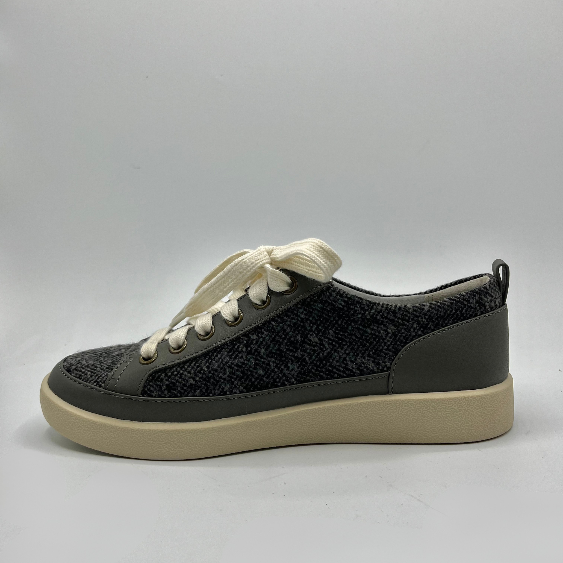 Grey sneaker with white laces on a gray background