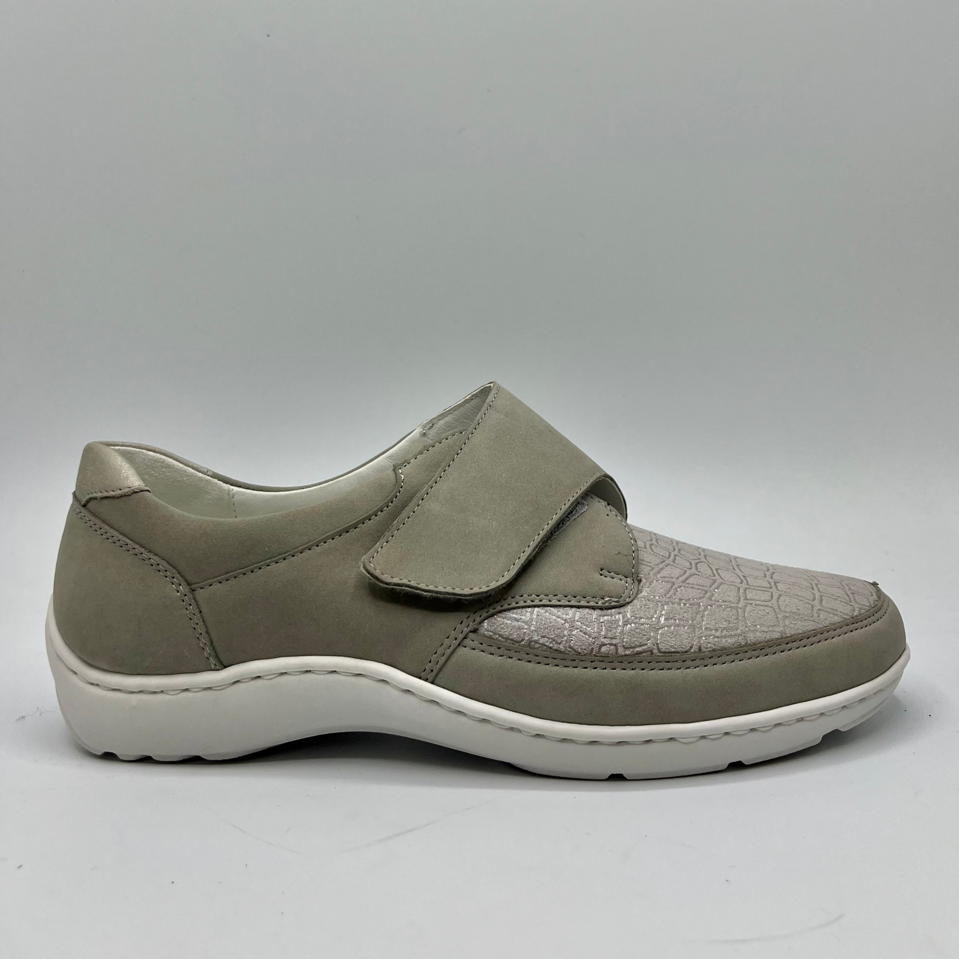 Right facing view of a grey sneaker with a velcro strap and a contoured footbed.