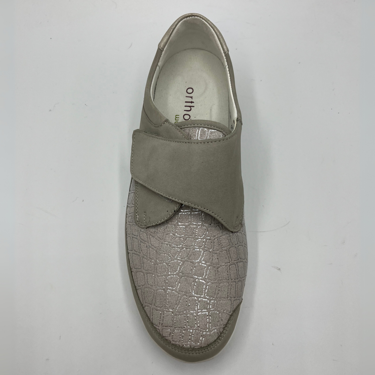 Top view of a grey sneaker with a velcro strap and a contoured footbed.