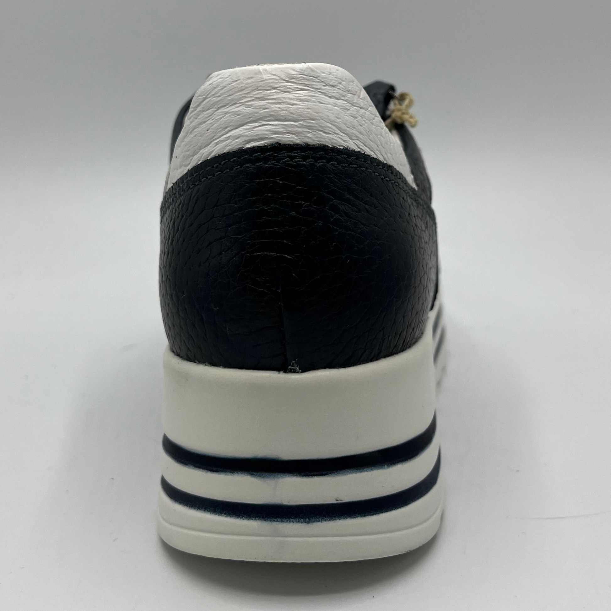 Back view of a navy leather sneaker with a white rubber outsole with laces and a side zipper closure.