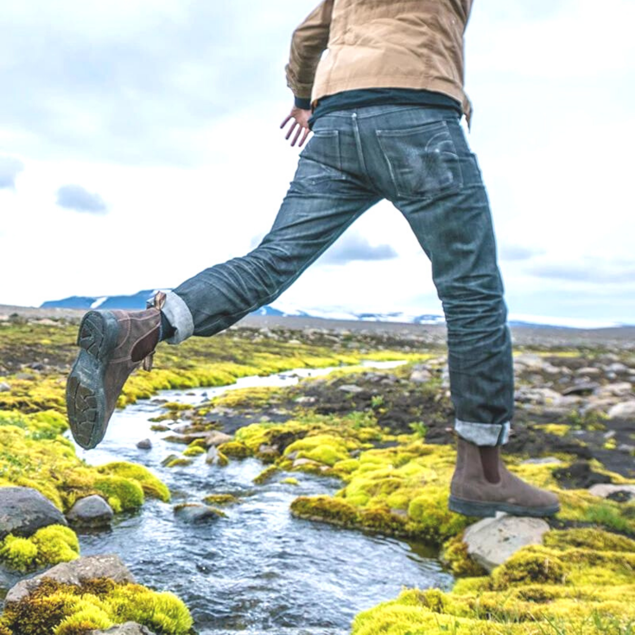 Man wearing classic chisel toe Blundstone, jumping over a tiny river