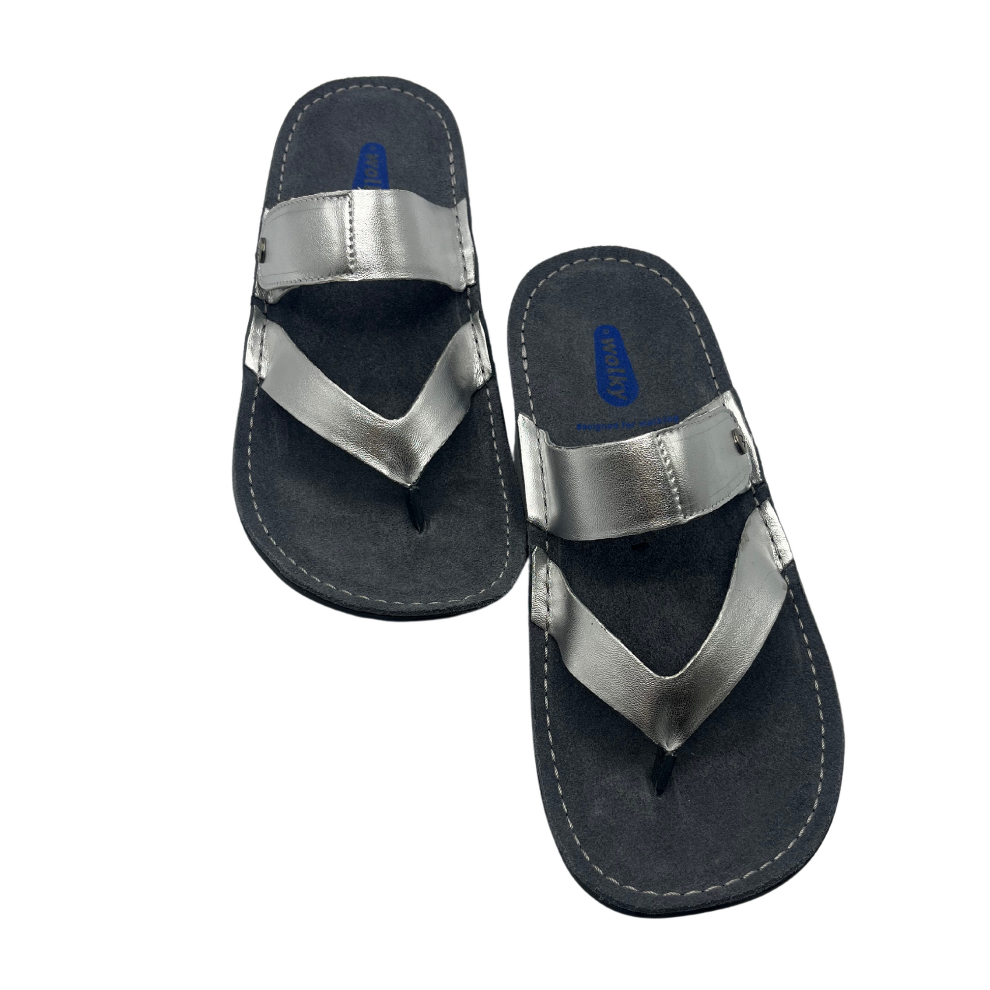 Top view of a pair of metallic silver sandals with a wedge heel and an adjustable strap
