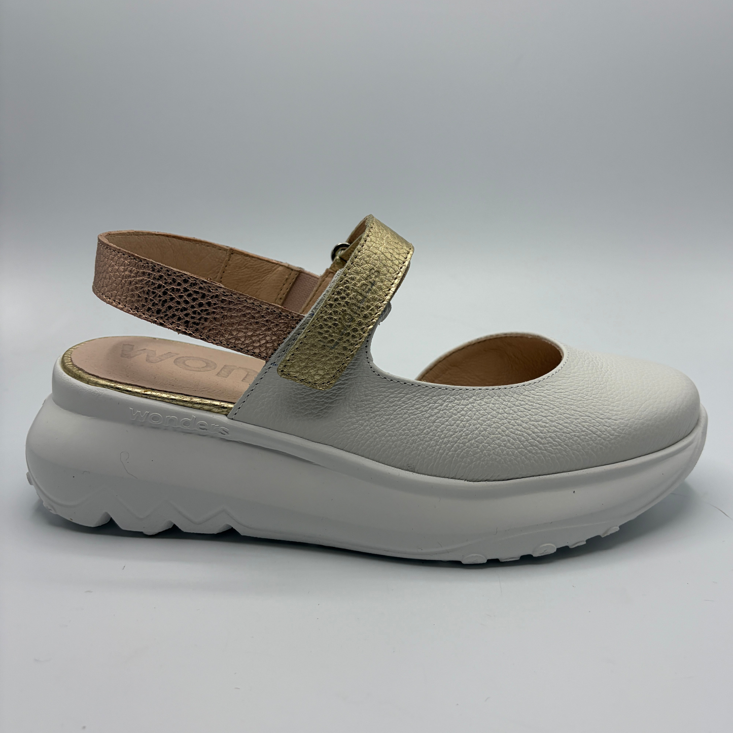 White shoe with brown and gold strap on a white background