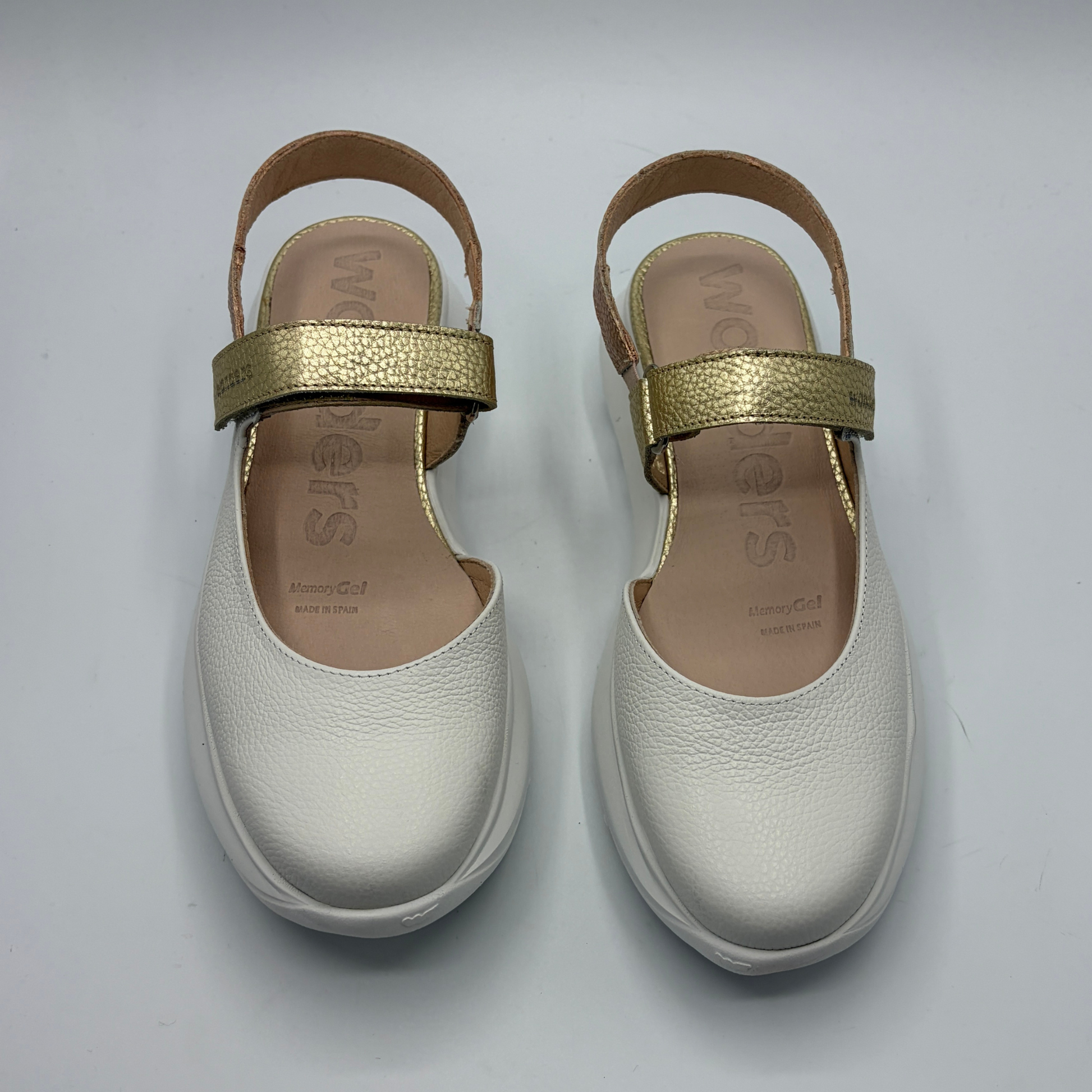 Pair of white shoes with gold straps on a light gray background
