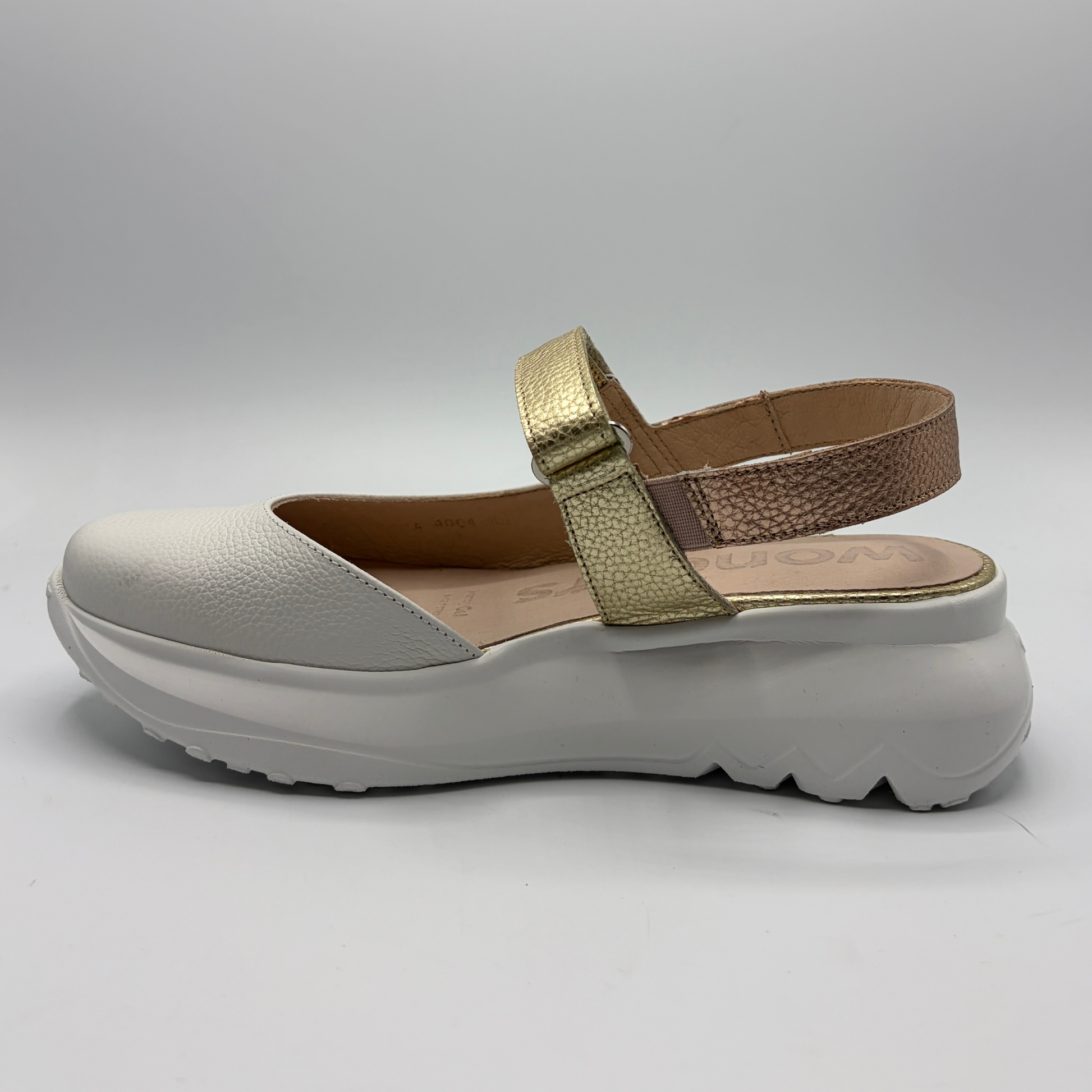 White sandal with gold strap on a light gray background