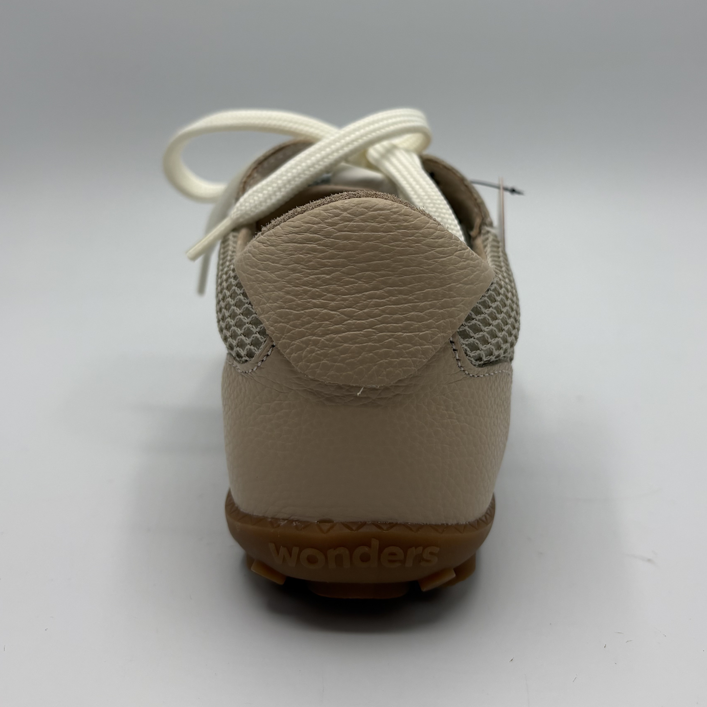 Beige shoe with white laces on a light gray background