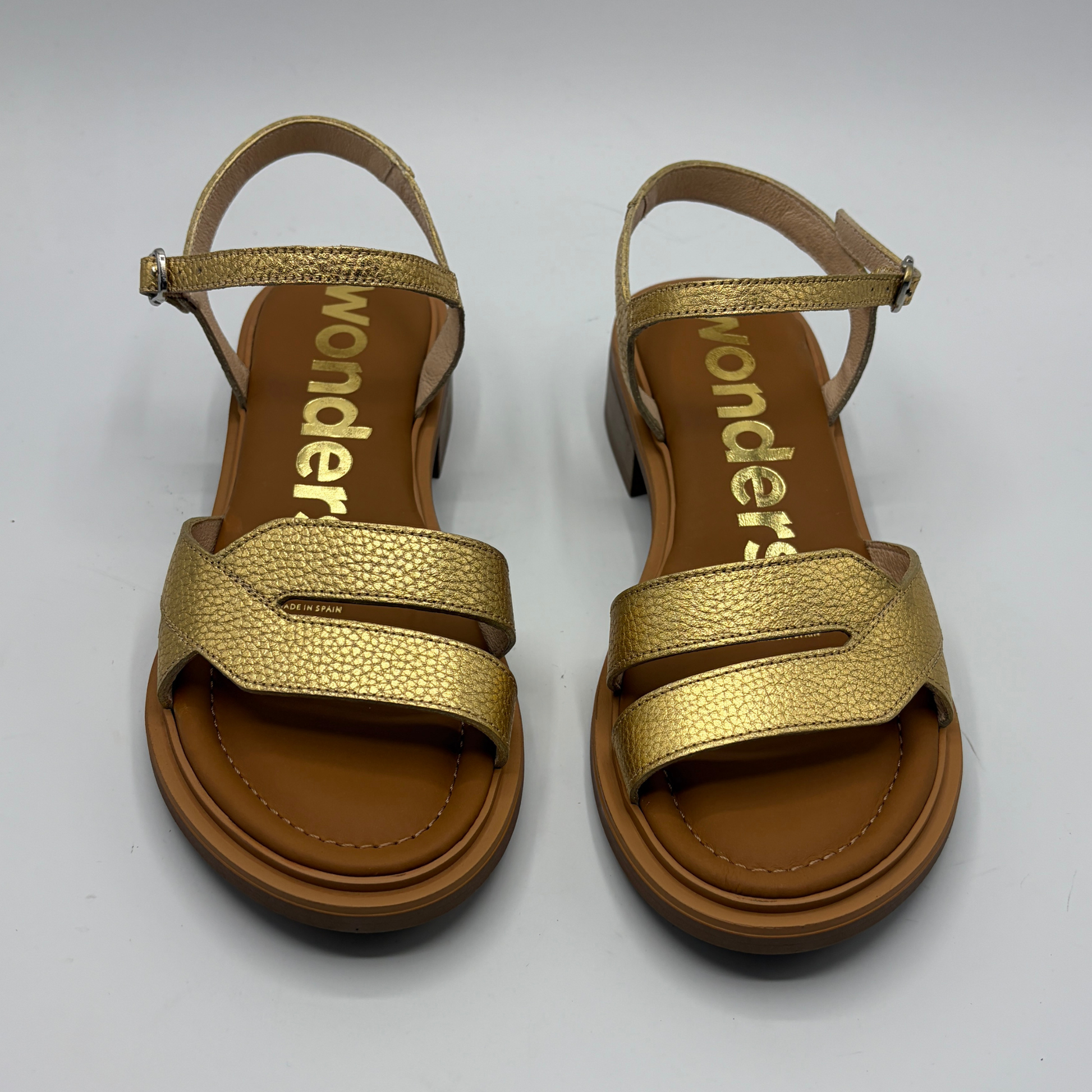 Gold sandals with brown soles on a white background