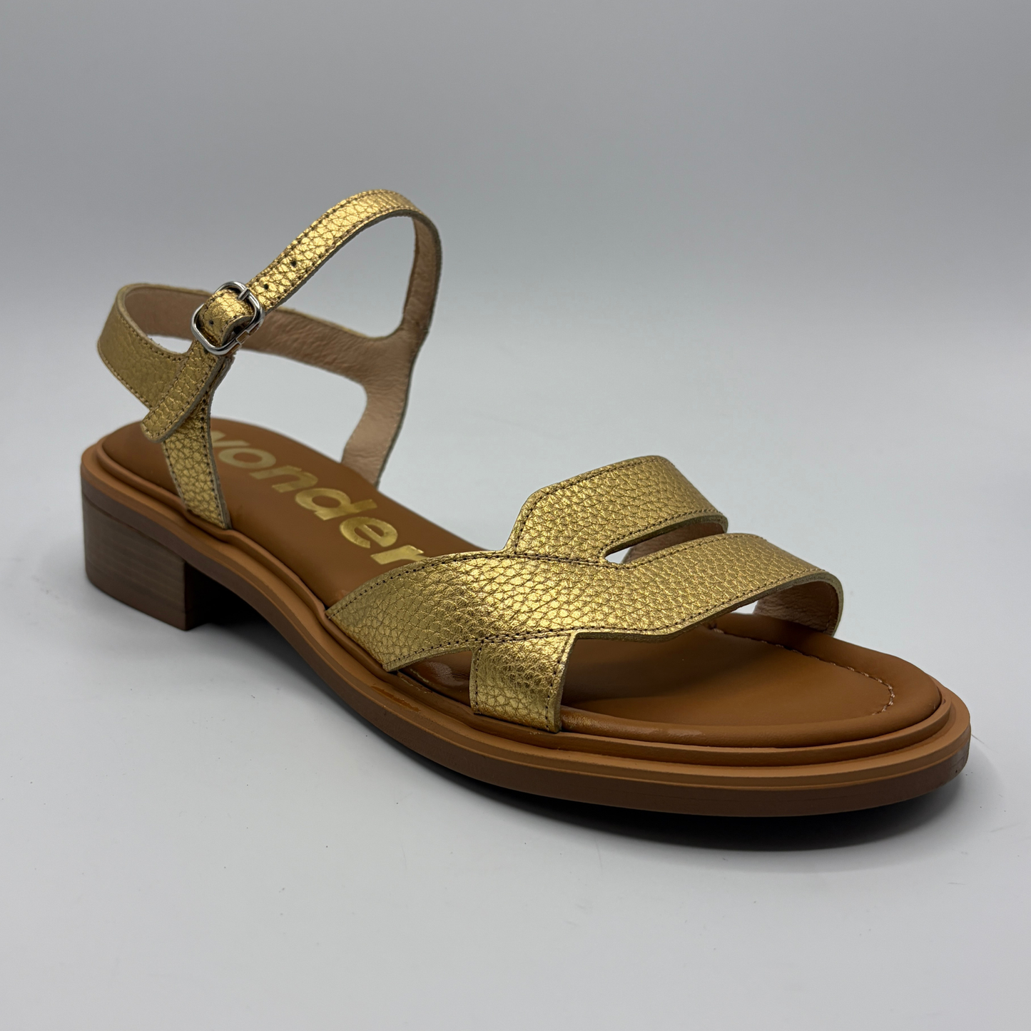 Gold sandal with brown sole on a gray background