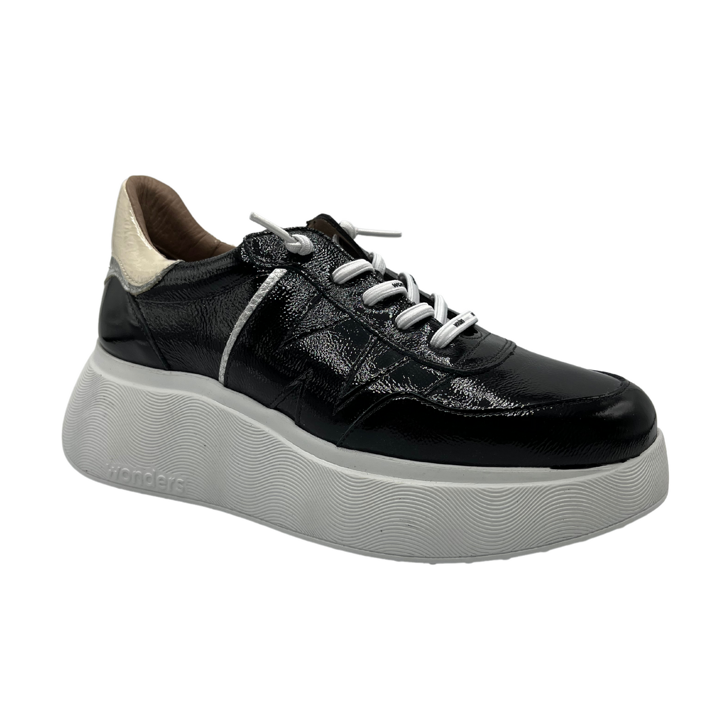 45 degree angled view of black patent leather sneaker with a padded heel and platform sole