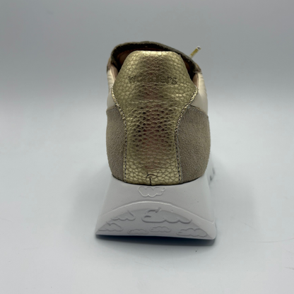 Back view of a sneaker with a textured gold sole on a gray background