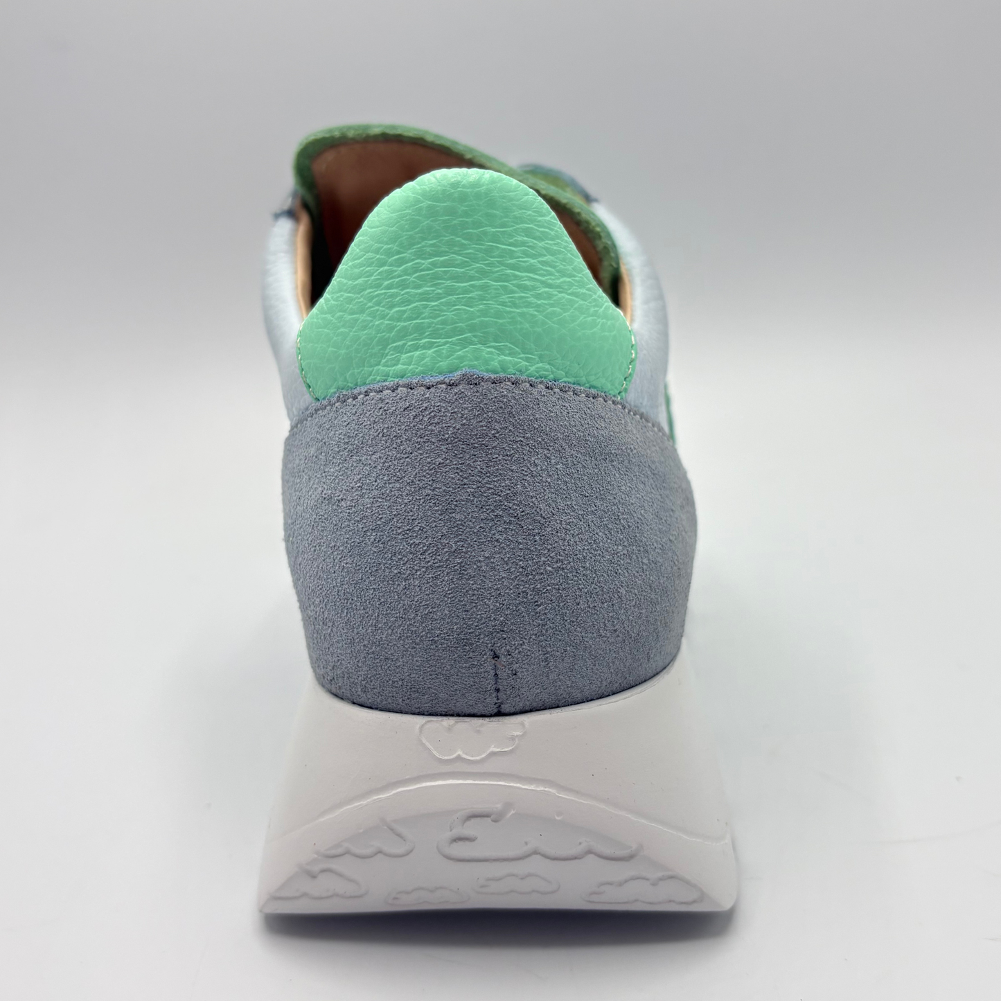 Gray sneaker with green heel collar on a light gray background