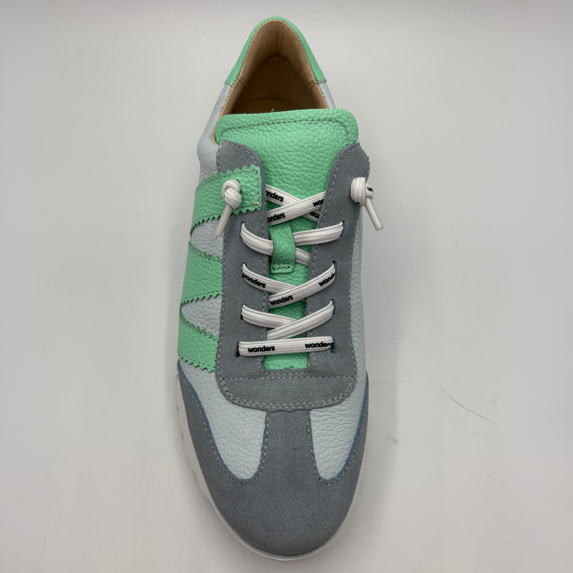 Gray and green sneaker with white laces on a light gray background