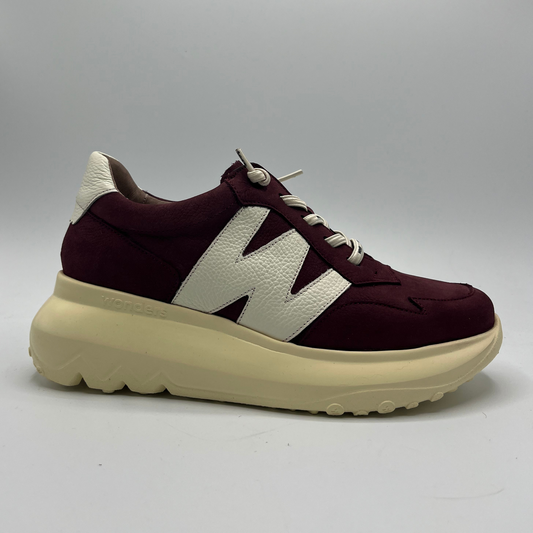Maroon sneaker with beige sole on a gray background