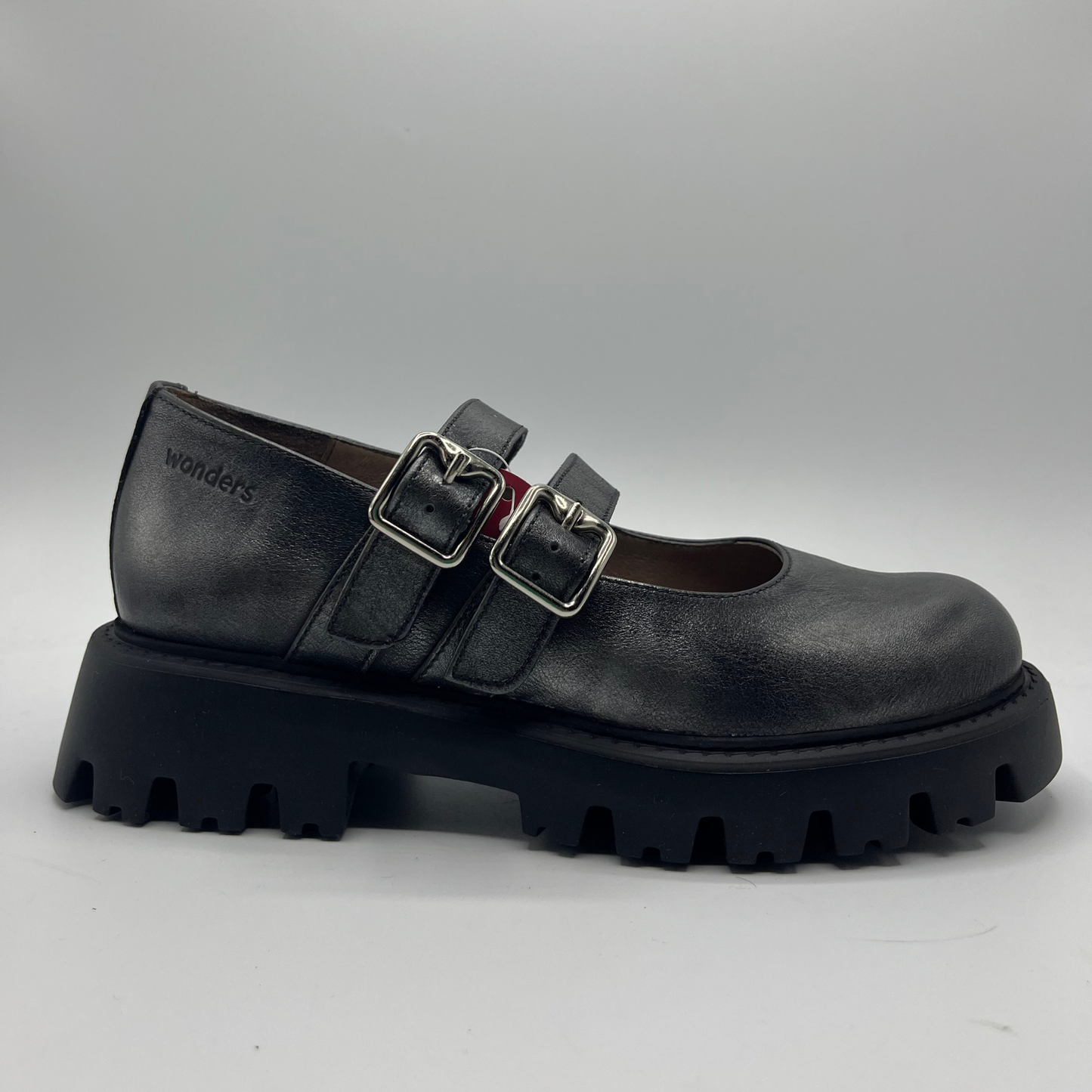 Black leather shoe with chunky sole and buckles on a gray background