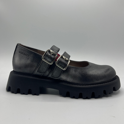 Black leather shoe with chunky sole and buckles on a gray background