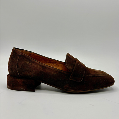 A single dark brown suede penny loafer with a low block heel, shown in profile against a neutral light gray background.