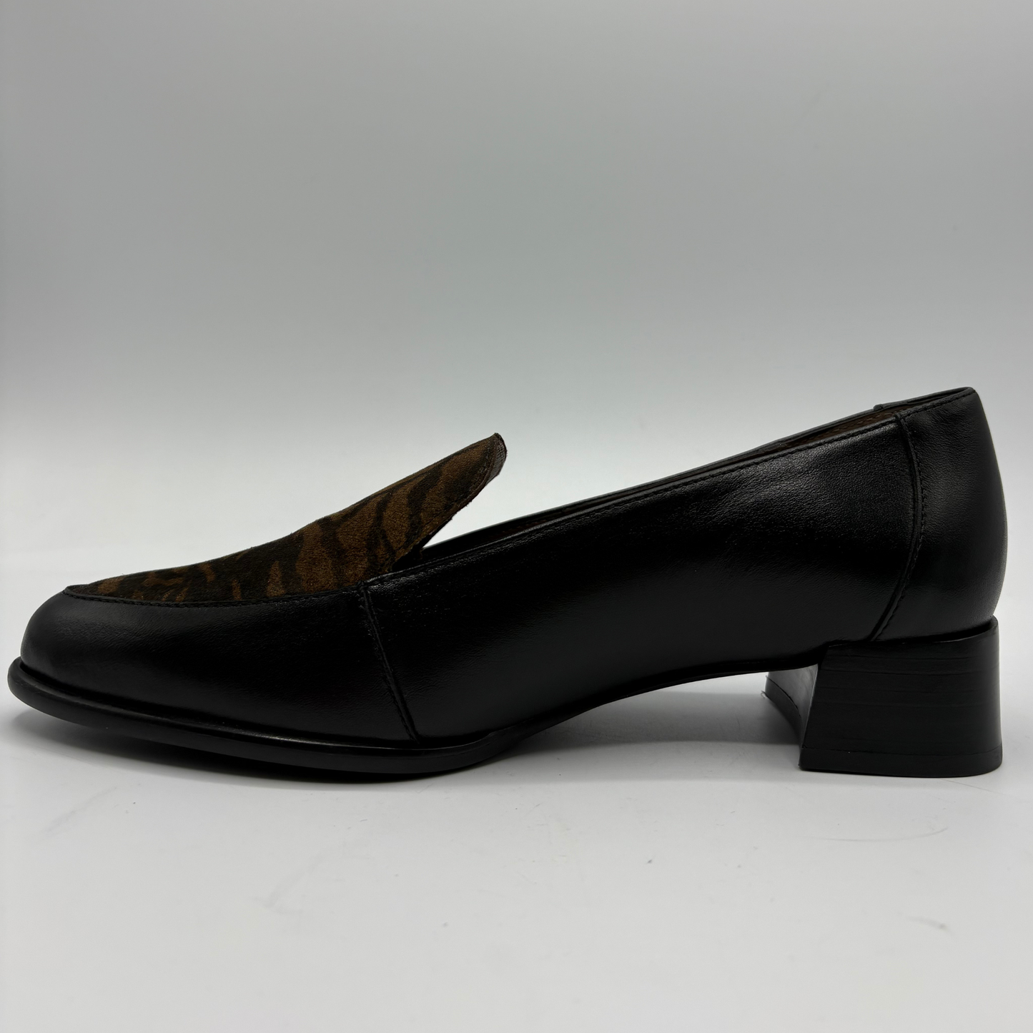 A single black leather loafer-style shoe with a low block heel, shown in side profile against a light gray studio background.