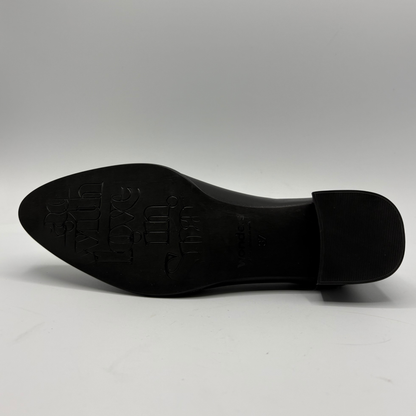 A black leather shoe sole with embossed branding, photographed from underneath against a neutral gray background.