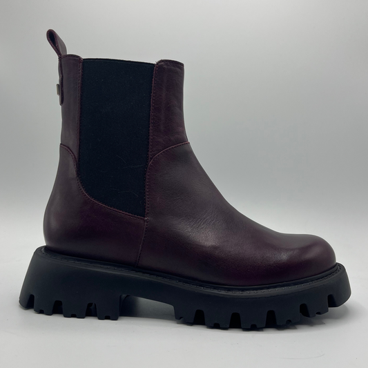Dark wine leather boot with thick black sole on a light gray background