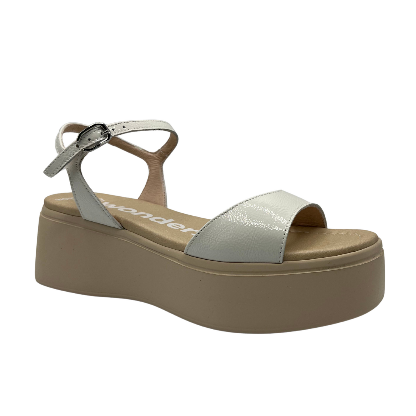 Angled view of a white and nude leather sandal with a platform sole, adjustable ankle strap with a silver buckle.