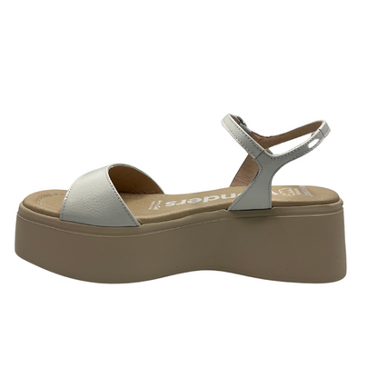 Left facing view of a white and nude leather sandal with a platform sole, adjustable ankle strap with a silver buckle.