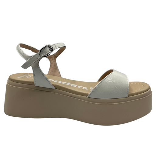 Right facing view of a white and nude leather sandal with a platform sole, adjustable ankle strap with a silver buckle.