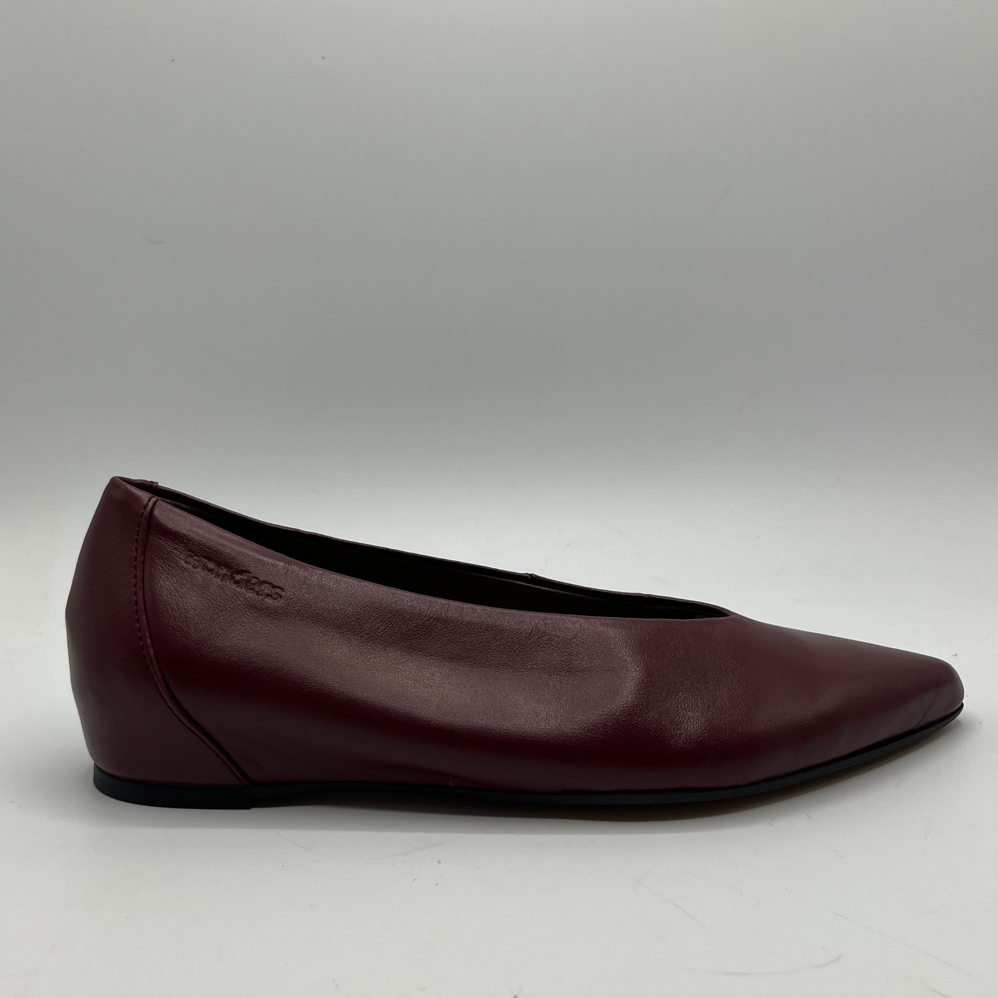 Burgundy leather flat shoe on a gray background