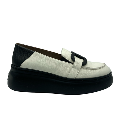 Outside view of a slip on loafer by Wonders. Black rubber sole. Leather upper is white all over except for heel wrap which is black