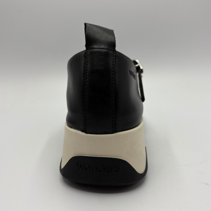 Black shoe with a white sole on a gray background