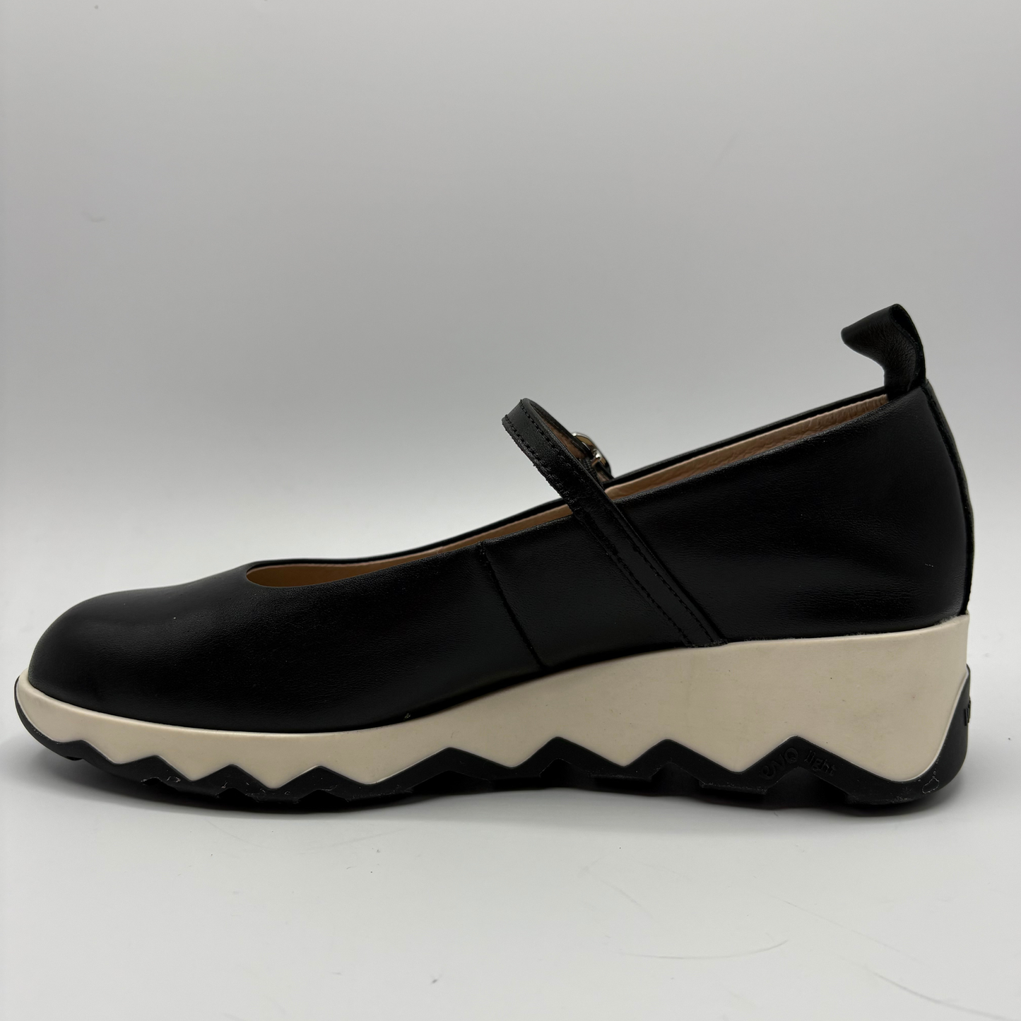 Black shoe with a white sole on a gray background