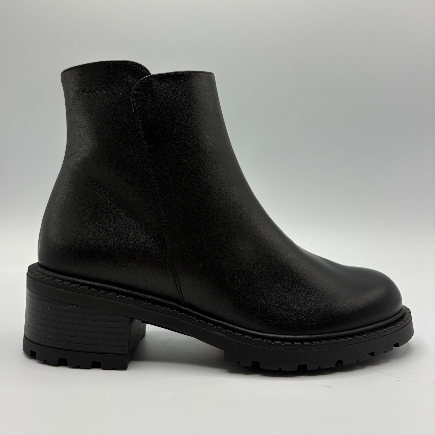 A single black leather ankle boot with a chunky block heel and lug sole, shown from a side profile against a light gray background.
