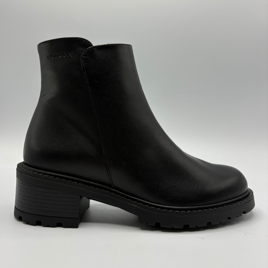 A single black leather ankle boot with a chunky block heel and lug sole, shown from a side profile against a light gray background.