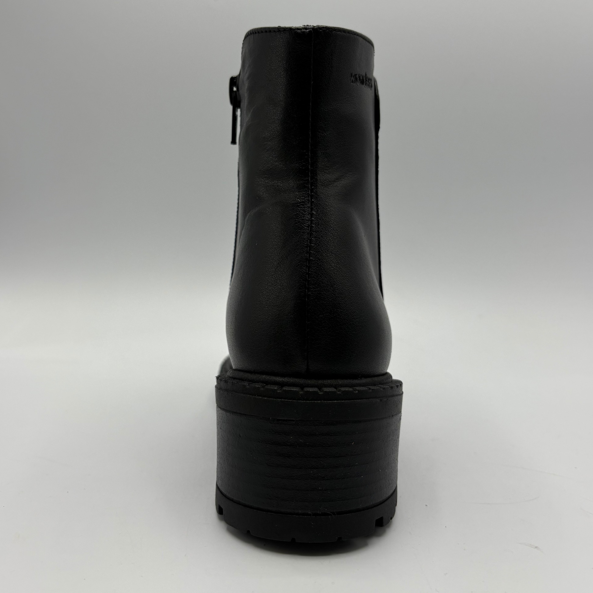 Black leather ankle boot with a chunky platform sole, shown from the back on a light gray background.