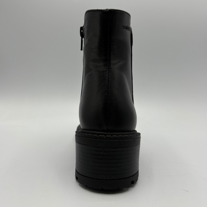 Black leather ankle boot with a chunky platform sole, shown from the back on a light gray background.