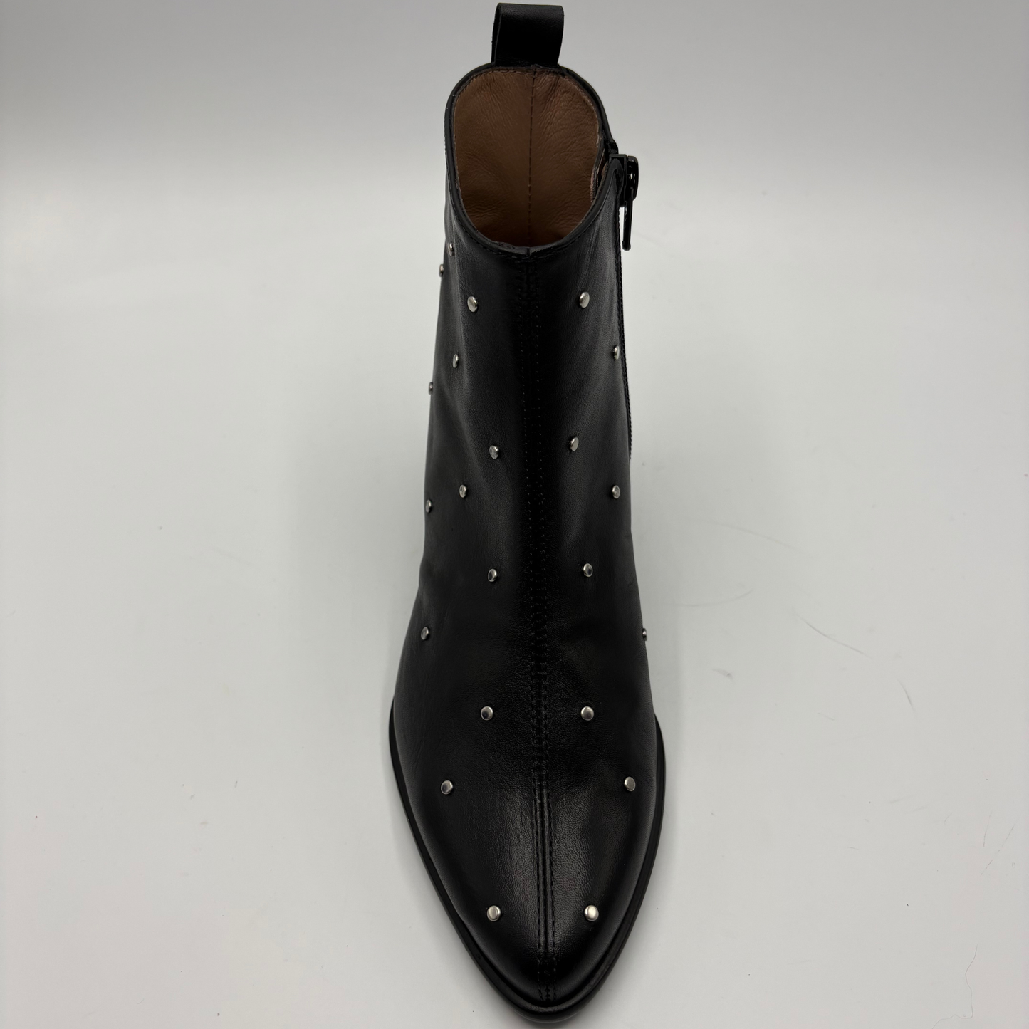 A black leather pointed-toe ankle boot with silver metal studs, shown from a top-down perspective on a light gray background.