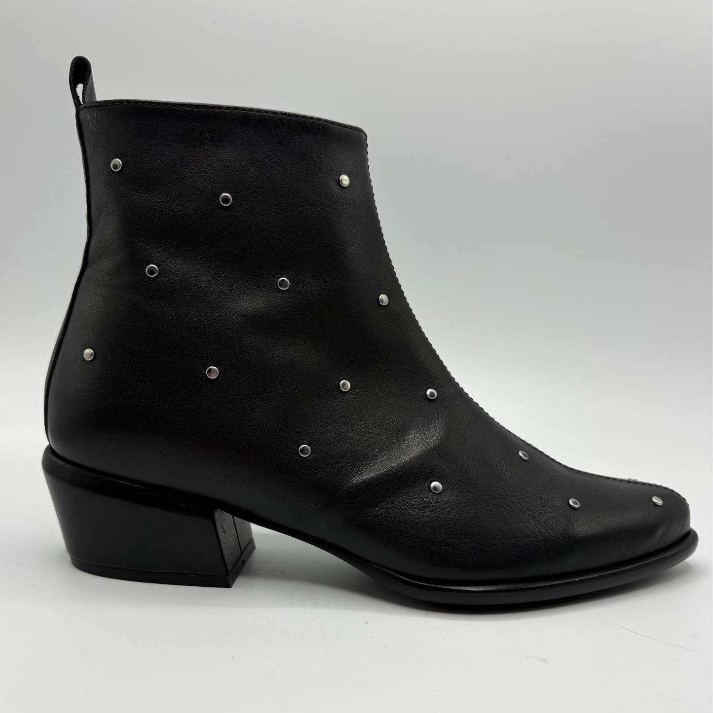 A black leather ankle boot with silver metal studs and a low block heel, shown from a side profile on a light gray background.