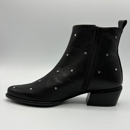 A black leather ankle boot with a low block heel, side zipper, and silver metal studs, shown from a side profile view on a light gray background.