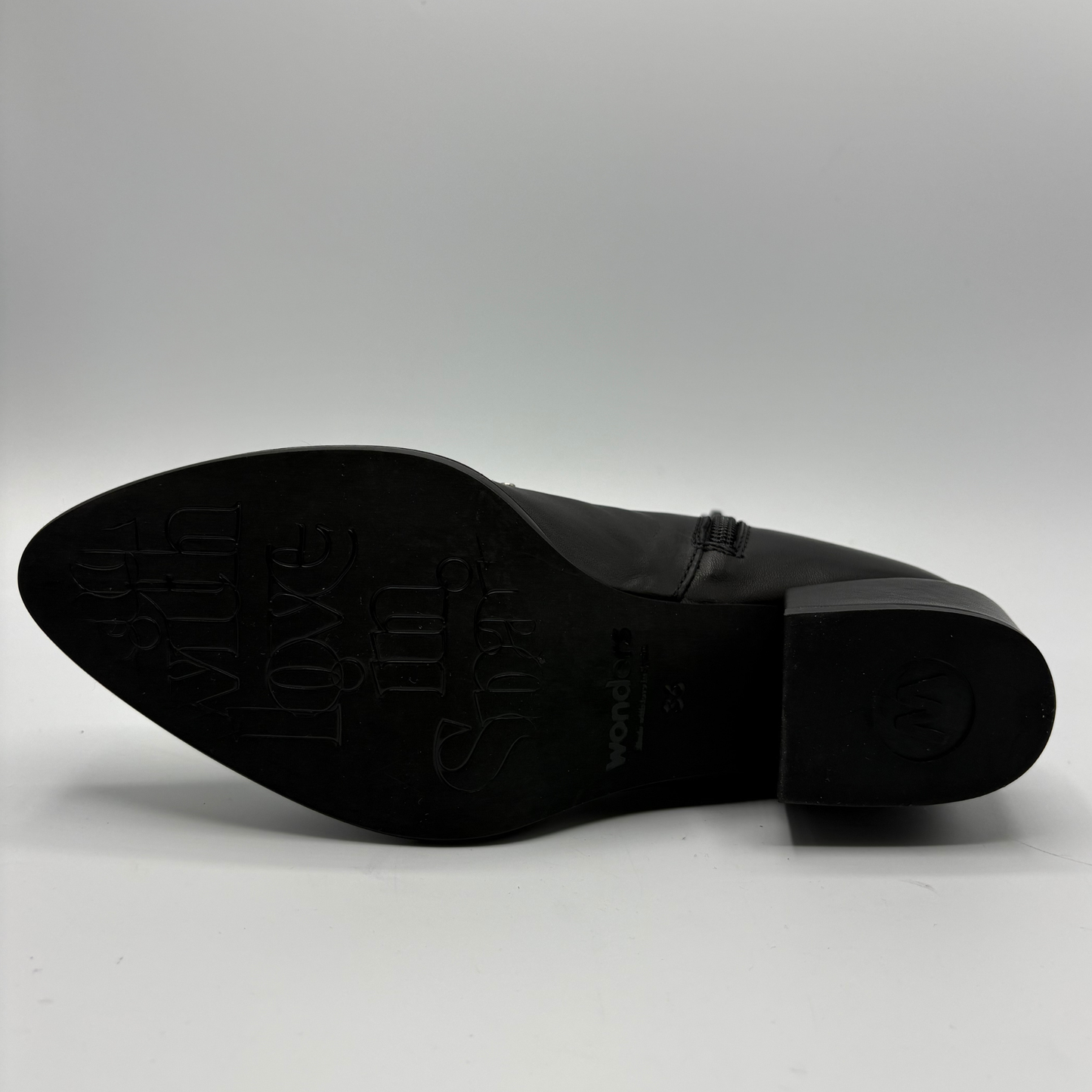 The black sole of a pointed-toe leather shoe photographed against a light gray background.
